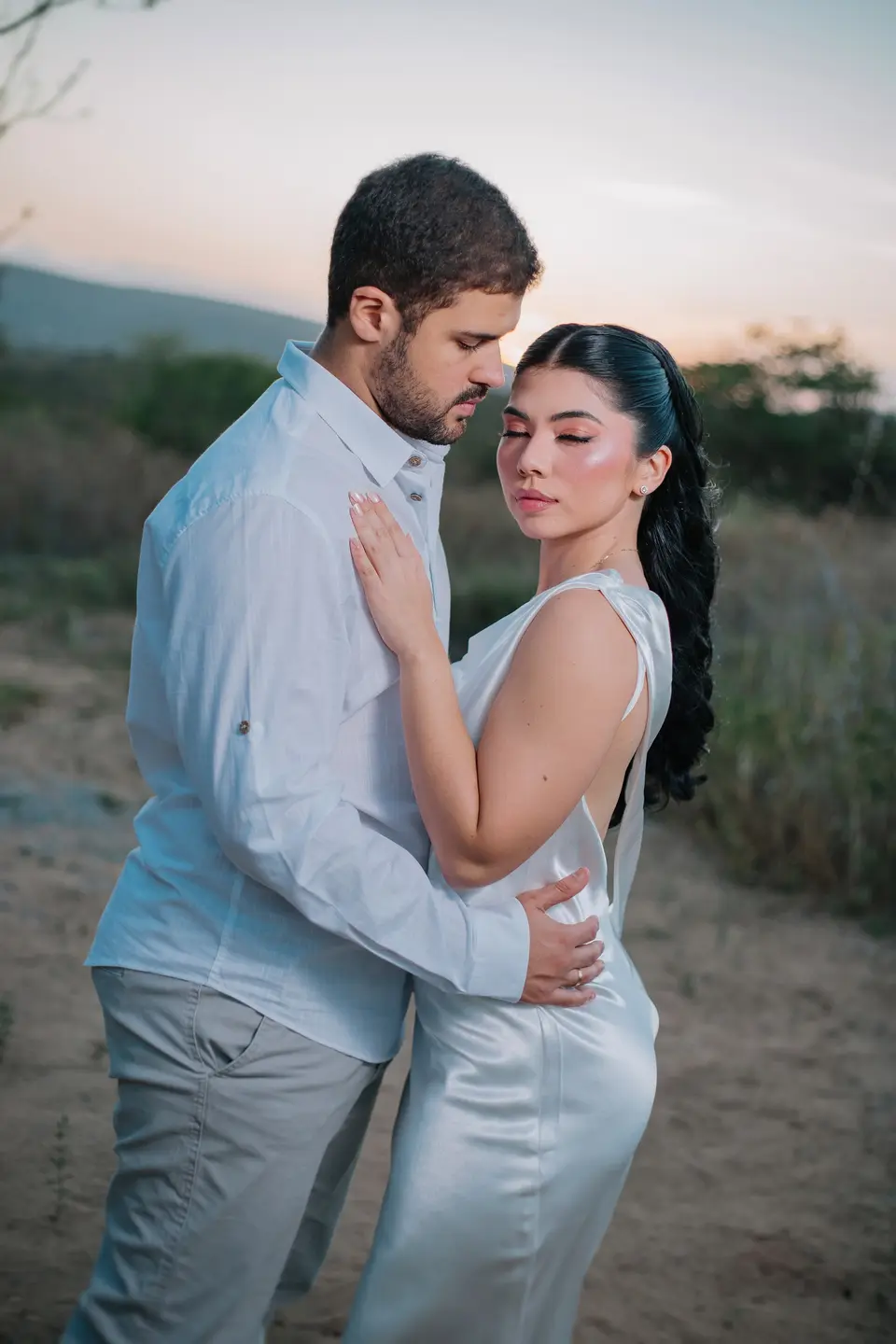 Jessica e Felipe abraçados em um campo, ao entardecer